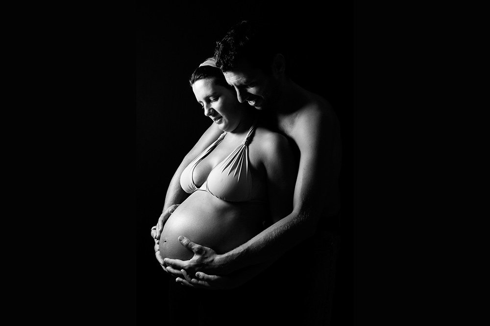 Mann umarmt Babybauch auf Schwarz Weiß Foto